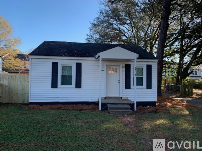 A small white house with a black roof and a front porch.