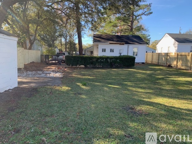 A backyard with a white fence and a house in the background.