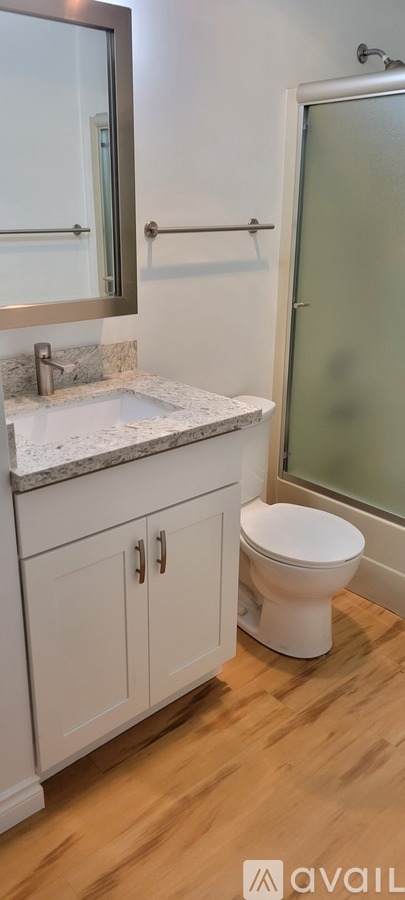 A bathroom with a toilet, sink, and mirror.