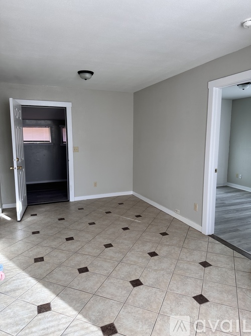 A room with a tile floor and a door leading to another room.