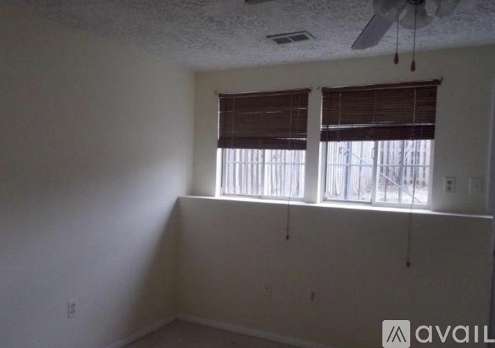 A room with a window covered by blinds and a ceiling fan.
