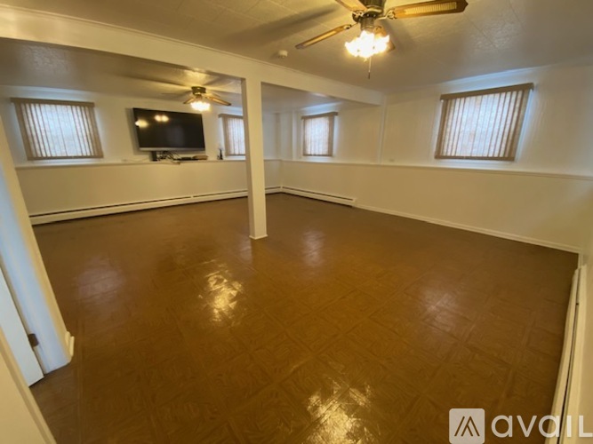 A spacious room with a ceiling fan and a television mounted on the wall.