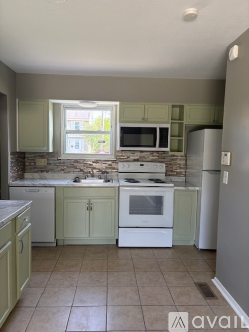 A kitchen with a white stove top oven and a white dishwasher.