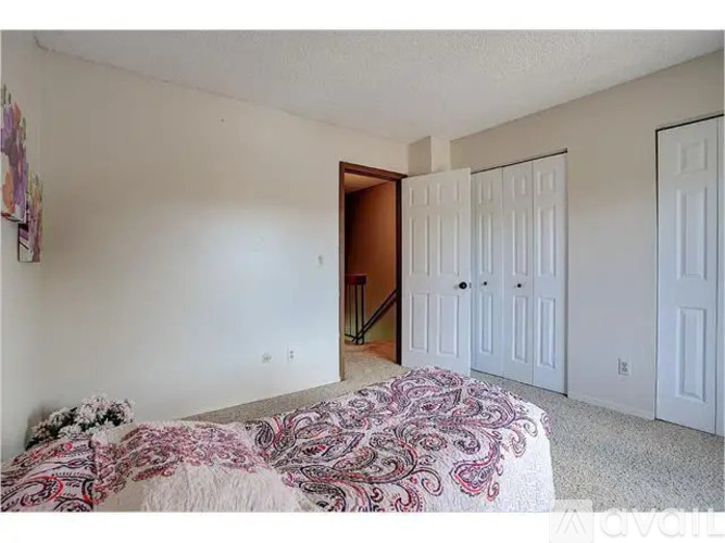 A bedroom with a bed and a doorway leading to another room.