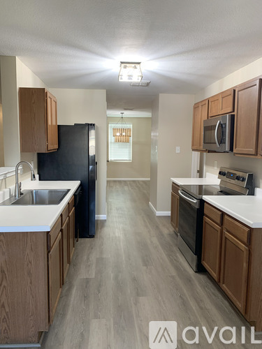 A kitchen with wooden cabinets and a black refrigerator.