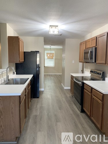 A kitchen with wooden cabinets and a black refrigerator.
