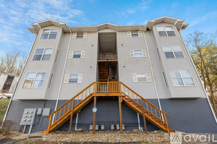 A modern two-story apartment building with a balcony and stairs leading to the entrance.