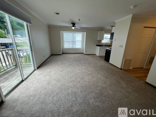A spacious room with a ceiling fan and sliding glass doors leading to a deck.