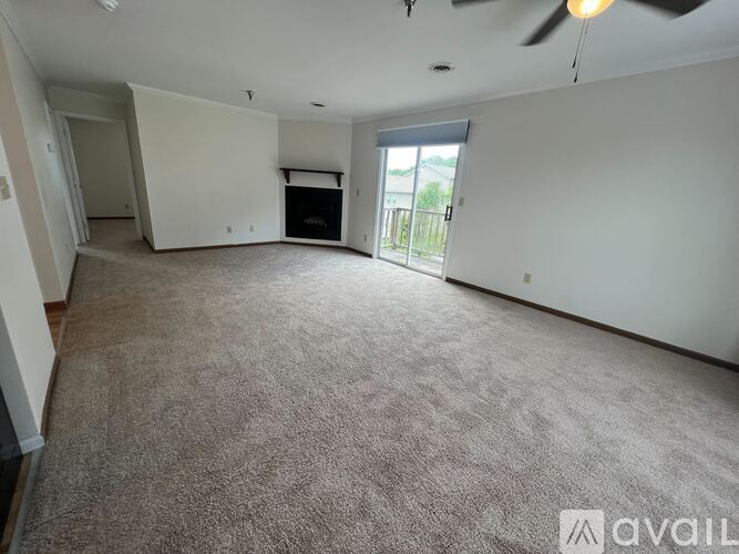 A spacious living room with a carpeted floor and a ceiling fan.