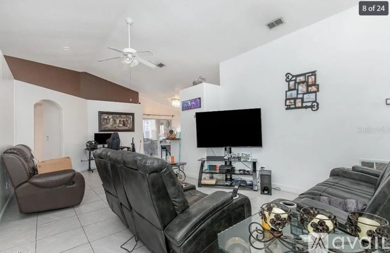 A living room with a black leather couch and a brown leather chair.