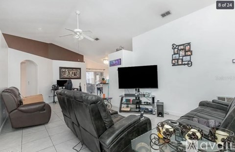 A living room with a black leather couch and a brown leather chair.