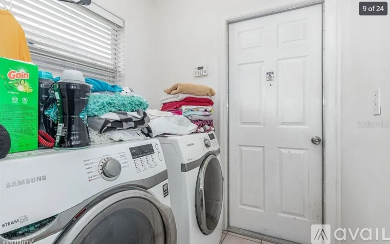 A white Samsung washing machine with a load of clothes on top of it.