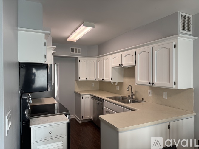 A kitchen with white cabinets and a black refrigerator.