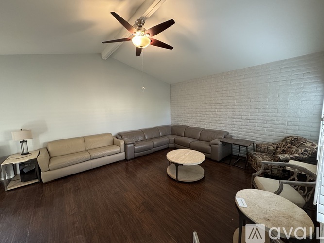 A living room with a white ceiling fan and a white brick wall.