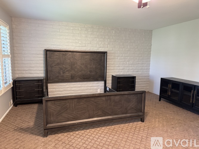 A bedroom with a bed, dresser, and a fireplace.
