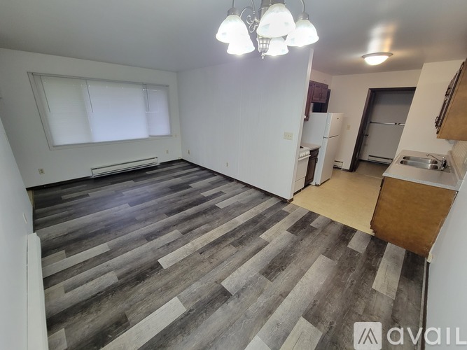 A spacious room with wooden flooring and a white wall.