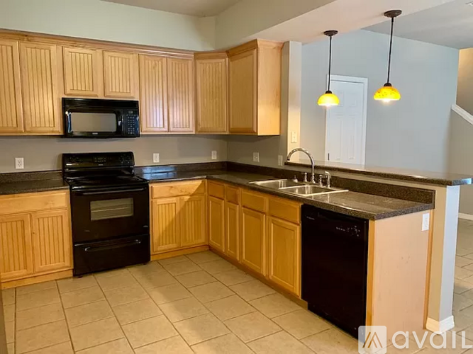 A kitchen with wooden cabinets and black appliances.
