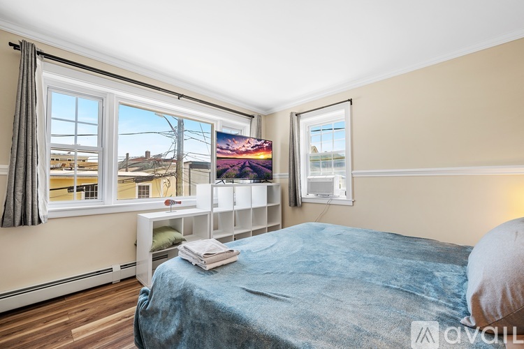 A bedroom with a large bed and a window overlooking a residential area.