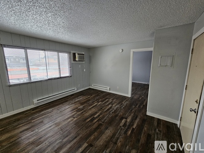 A room with wood flooring and a window with blinds.