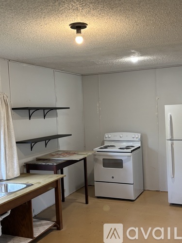 A small kitchen with a stove, refrigerator, and a table.