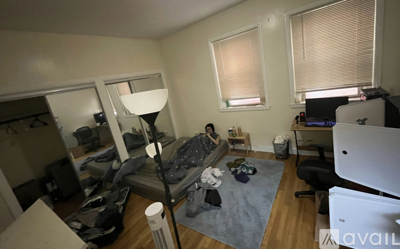A living room with a couch, a chair, a table, a lamp, a window, and a TV.