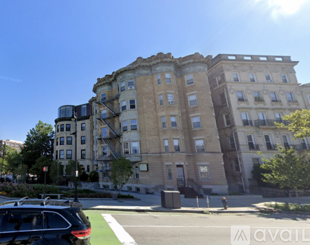 A black car is parked on the side of a street in front of a large building.