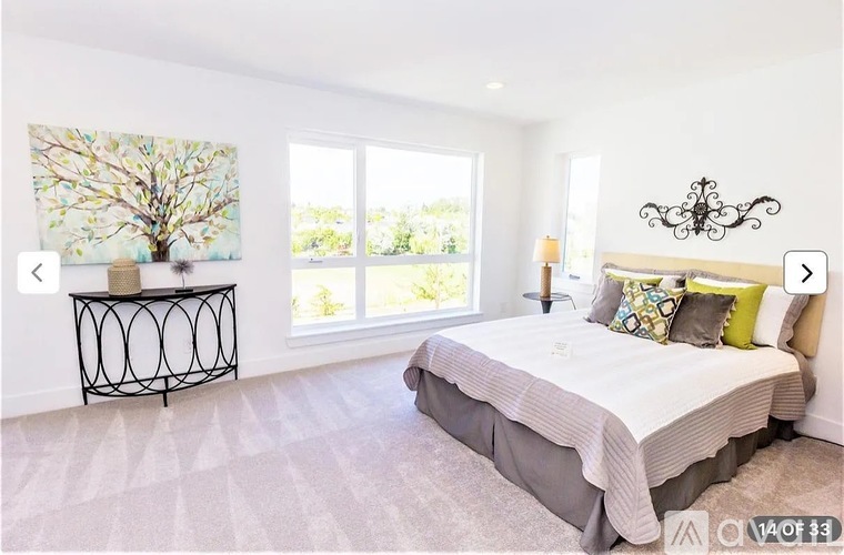 A bedroom with a large bed and a tree painting on the wall.