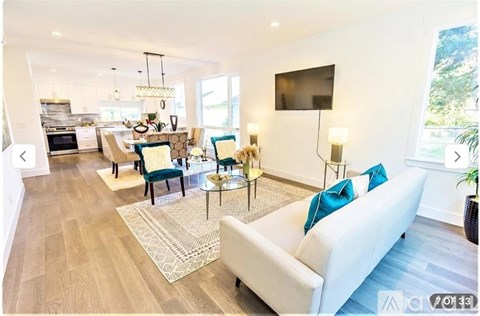 A modern living room with a white sofa and a television on the wall.