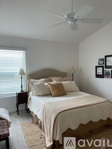A bedroom with a bed, a fan, and pictures on the wall.
