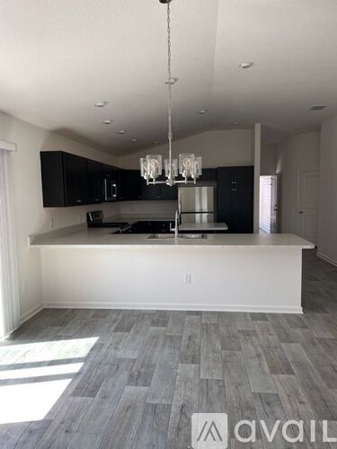 A kitchen with a white island and a chandelier hanging from the ceiling.