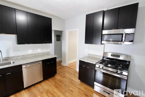 A kitchen with black cabinets and a stainless steel oven.