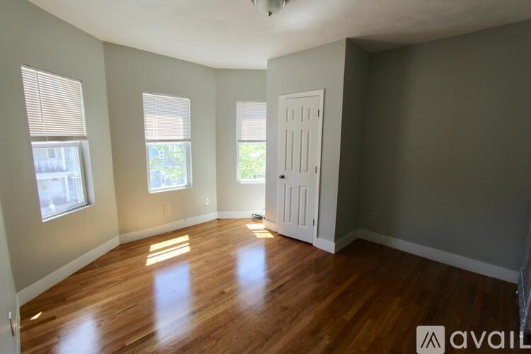 A room with wooden floors and three windows.
