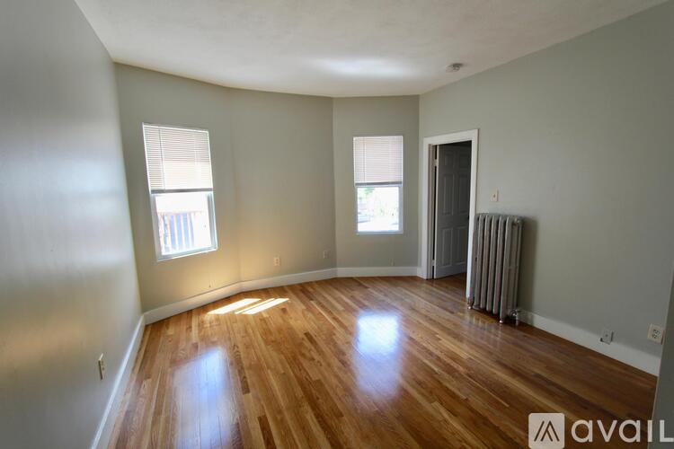 A room with wooden floors and a window with blinds.