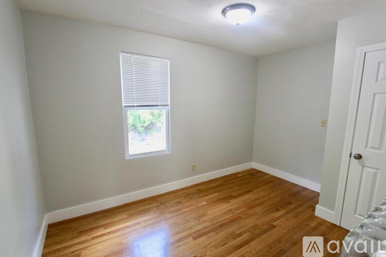 A room with wooden flooring and a window with blinds.