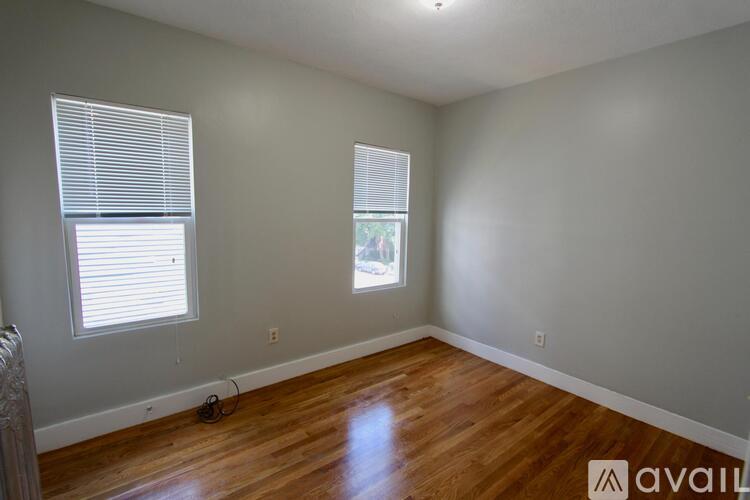 A room with wooden floors and two windows.