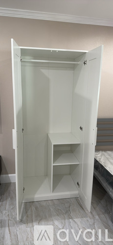 A white wardrobe with two shelves is open.
