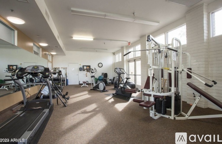 A gym with a variety of equipment including treadmills, weights, and exercise machines.