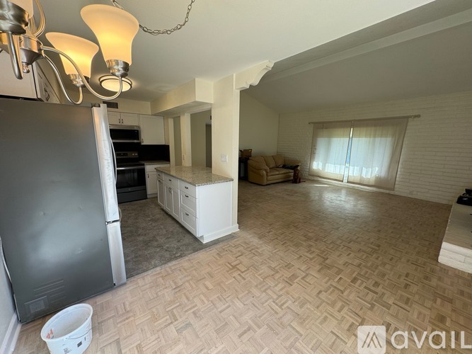A kitchen with a refrigerator, cabinets, and a chandelier.