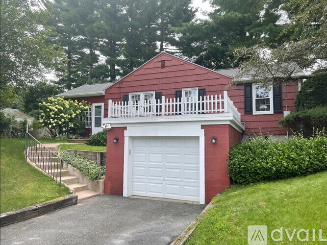 A red house with a white garage door and a white fence.