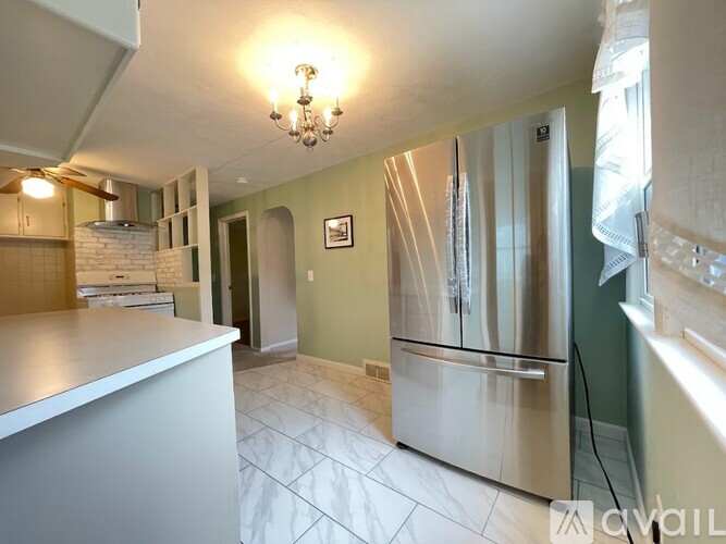 A kitchen with a stainless steel refrigerator and a chandelier hanging from the ceiling.