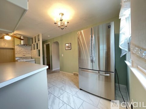 A kitchen with a stainless steel refrigerator and a chandelier hanging from the ceiling.