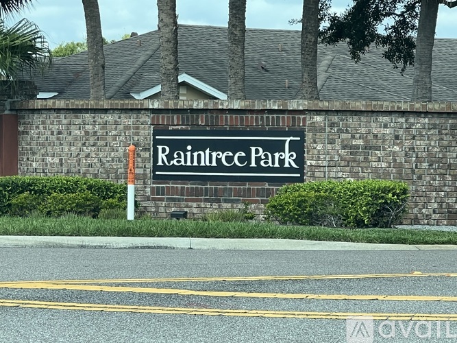A sign that says Raintree Park is on a brick wall.