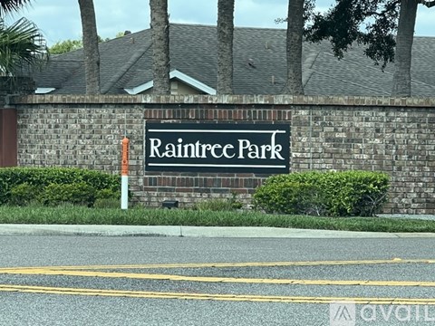 A sign that says Raintree Park is on a brick wall.