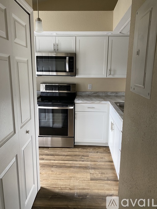 A kitchen with white cabinets and a wooden floor.