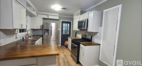 A kitchen with white cabinets and a wooden counter top.