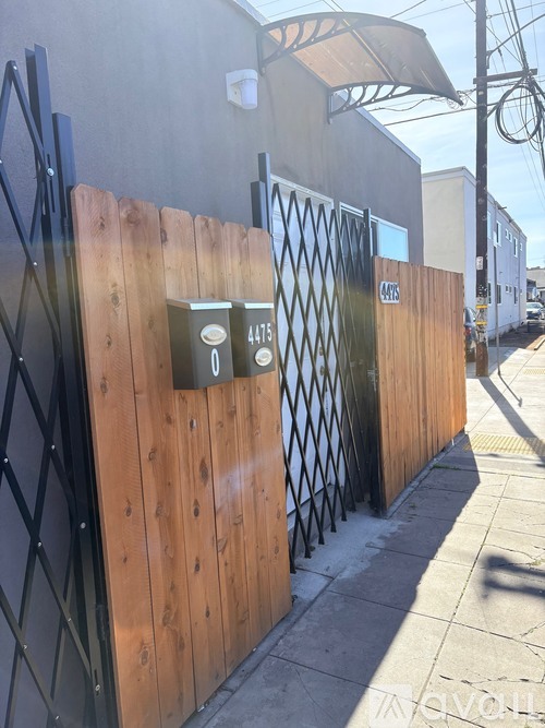 A wooden fence with a metal gate and a lock box on it.