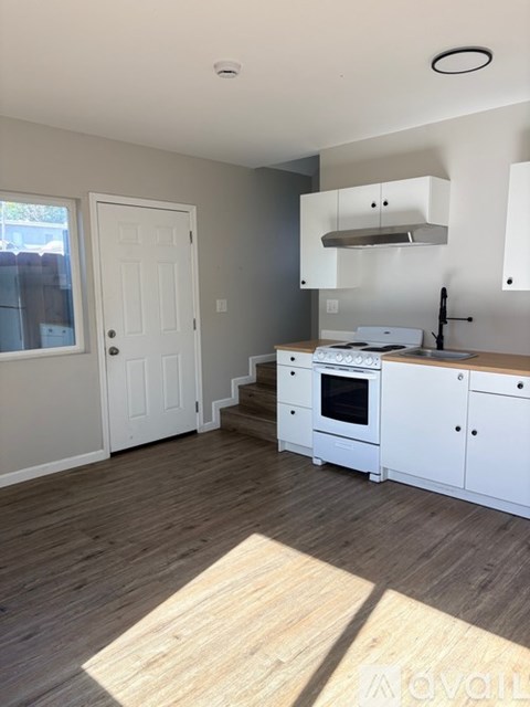 A kitchen with white cabinets and a stove top oven.
