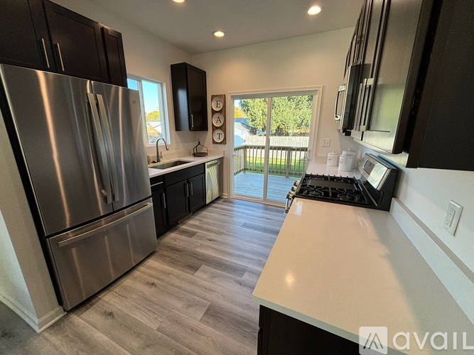 A kitchen with a stainless steel refrigerator and wooden flooring.