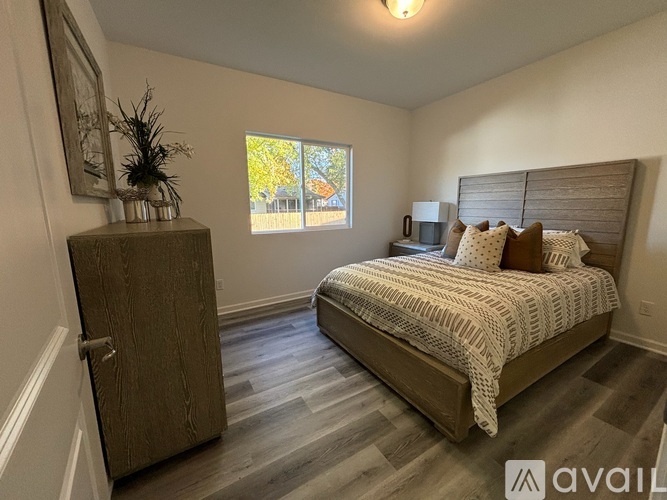 A bedroom with a bed, wooden dresser, and a window.