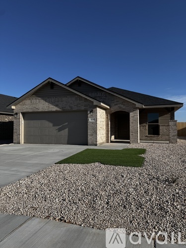 A modern house with a grey garage door and a stone wall in front.